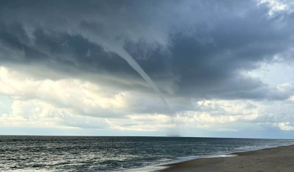 A waterspout descends from a dark storm cloud just off the shoreline south of Ramp 23 on Hatteras Island.